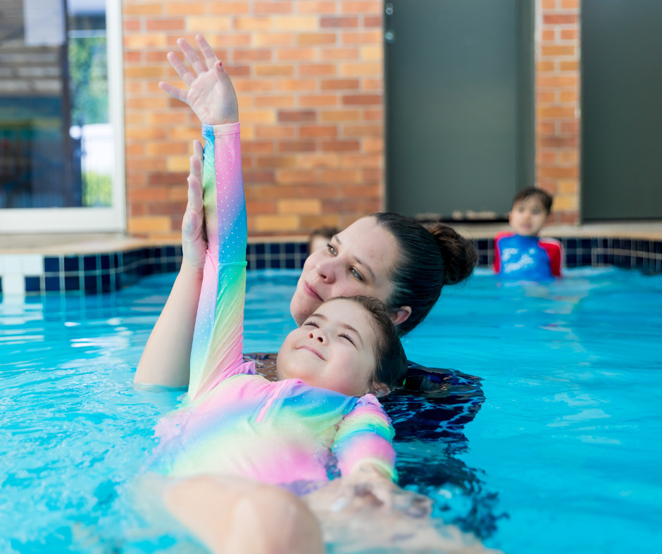 Child learning to float with instructor during swimming lesson