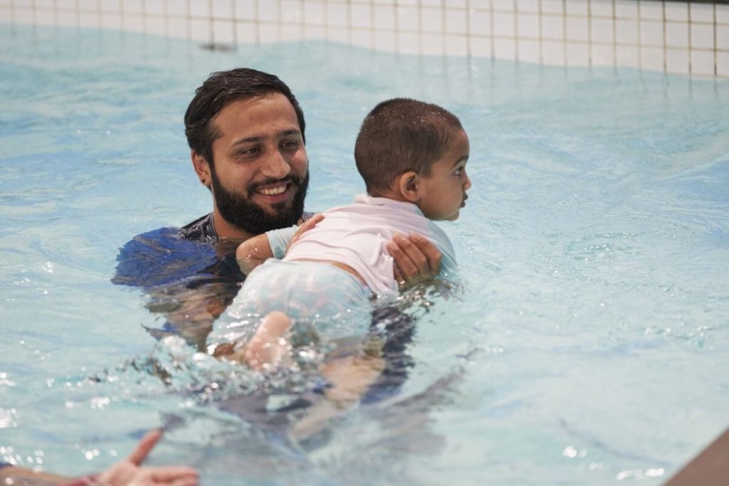 Baby practising swimming with support during an infant swimming lesson