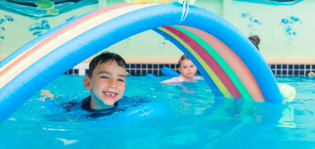 Confident young swimmer enjoying a swimming lesson after developing skills and water confidence through regular lessons.