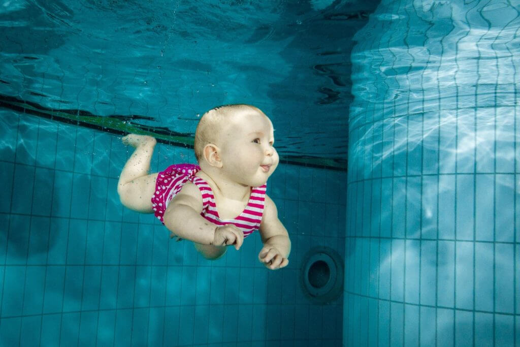 Baby demonstrating confidence in the water during an infant swimming lesson.